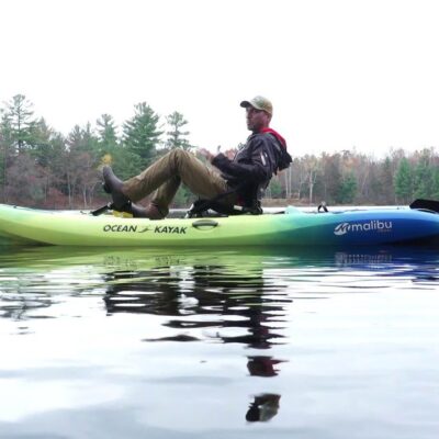 an ocean kayak in the water with a man pedalling