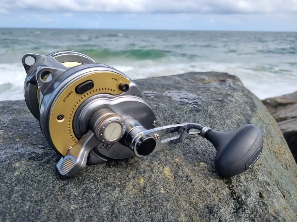 Shimano Tyrnos Reel sitting on a rock in front of the ocean without a rod in free-spool mode