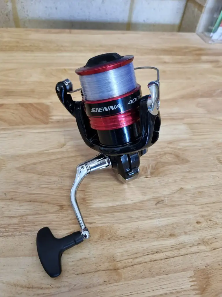 Shimano Sienna 4000 reel sitting on a bench focused on the handle